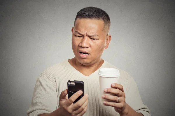 Worried man reading bad news on smart phone drinking cup of coffee — Stock Photo, Image