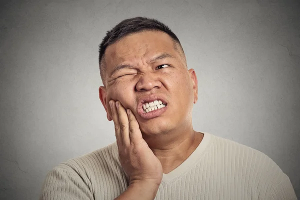 Человек, прикоснувшийся к лицу, испытывает сильную боль, зубную боль — стоковое фото