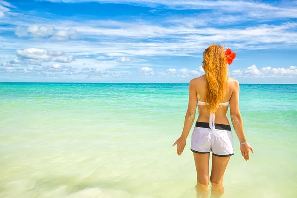 Kadının tropikal plaj tropikal mavi su tarafından yaz aylarında neşeli rahatlatıcı — Stok fotoğraf