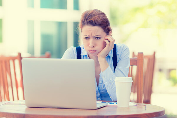 displeased worried business woman sitting in front of laptop computer
