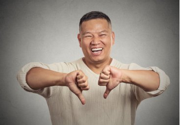 iki başparmak işareti el hareketi aşağı gösterilen alaycı genç adam