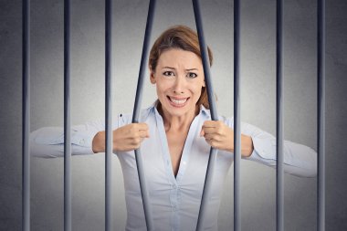 Stressed desperate angry businesswoman bending bars of her prison 