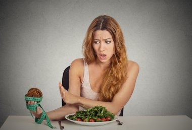 woman deciding whether to eat healthy food or sweet cookies she craving clipart