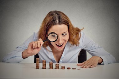 greedy business woman looking at stack of coins through magnifying glass  clipart