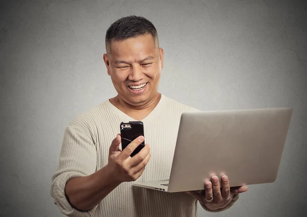 Happy förvånad man läsa nyheter på smart telefon hålla laptop — Stockfoto