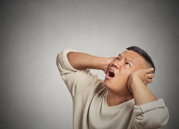 Arg galen olycklig stressad man som täcker öronen tittar upp — Stockfoto