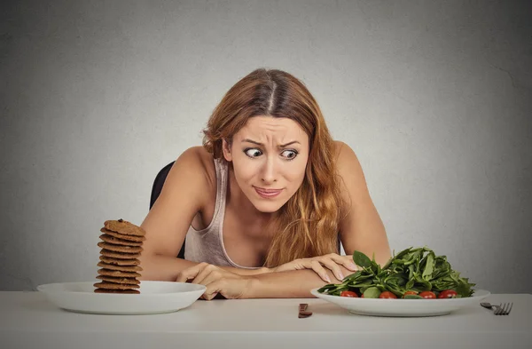 Woman deciding whether to eat healthy food or sweet cookies she craving — Stock Photo, Image