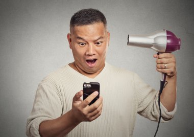 saç kurutma makinesi tutan smartphone üzerinde seyir şaşırmış adam şok