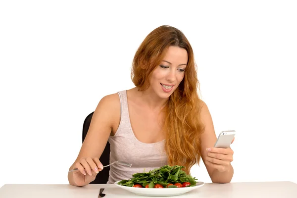 Young woman eating and chatting on mobile phone isolated white background — Stock Photo, Image