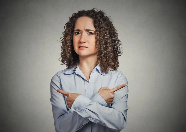 Verwirrte junge Frau zeigt in zwei verschiedene Richtungen — Stockfoto