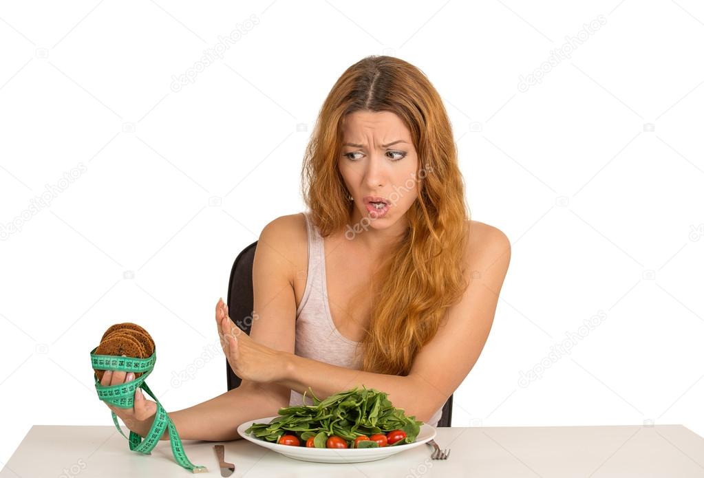 woman deciding whether to eat healthy food or sweet cookies