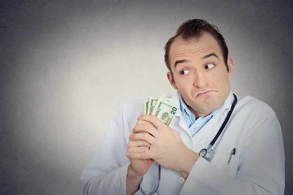 Grumpy greedy miserly health care professional holding money — Stock Photo, Image