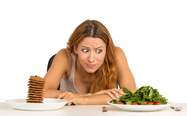 Woman deciding whether to eat healthy food or sweet cookies — Stock Photo, Image