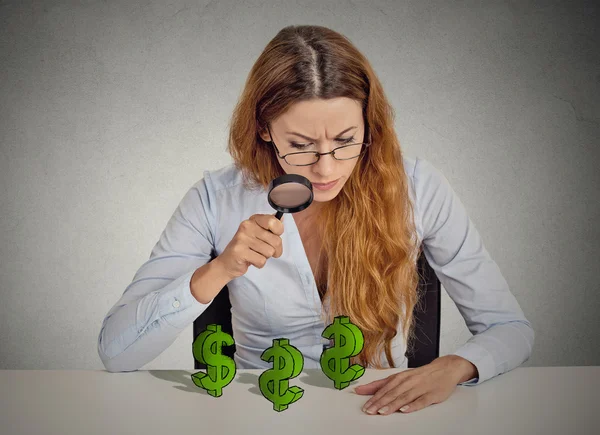 Affärskvinna tittar genom förstoringsglas på dollartecken — Stockfoto