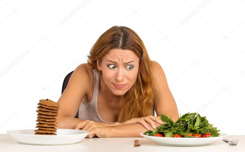 woman deciding whether to eat healthy food or sweet cookies