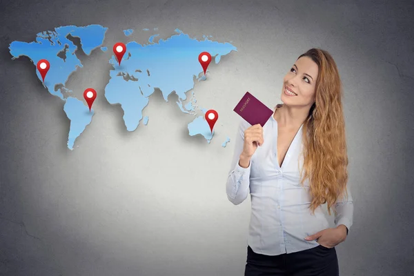 Туристическая молодая женщина с паспортом стоя смотрит на карту мира — стоковое фото
