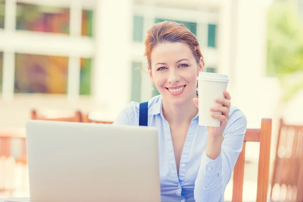 Lachende vrouw die op laptop buiten hoofdkantoor drinken koffie werkt — Stockfoto