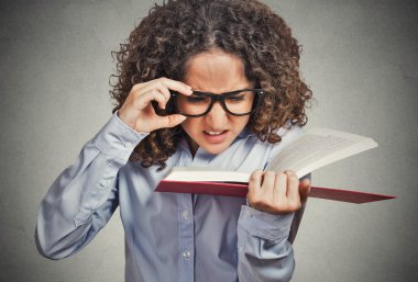 woman with eye glasses trying to read book, having difficulties seeing text clipart