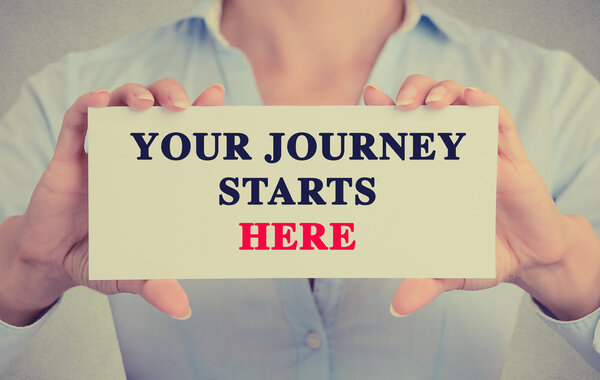 Деловая женщина руки держащие карточку знак с вашим путешествием начинается здесь сообщение
