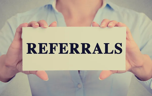 Businesswoman hands holding white card sign with referrals text message — Stock Photo, Image