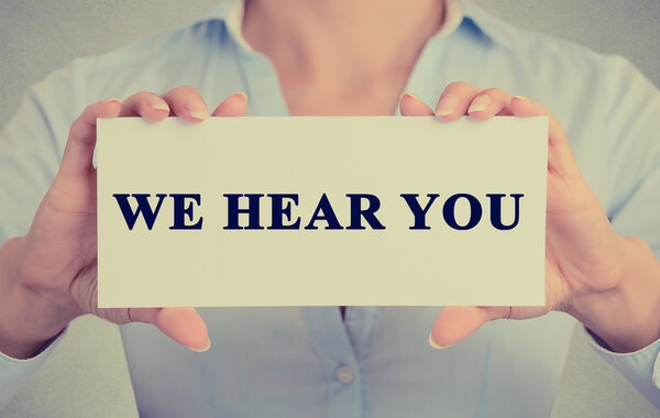 Деловая женщина руки держа карточку знак с мы слышим ваше сообщение
 