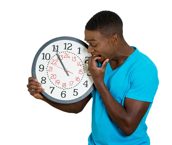 Homem segurando relógio de parede, estressado mordendo unhas pressionadas pela falta de tempo — Fotografia de Stock