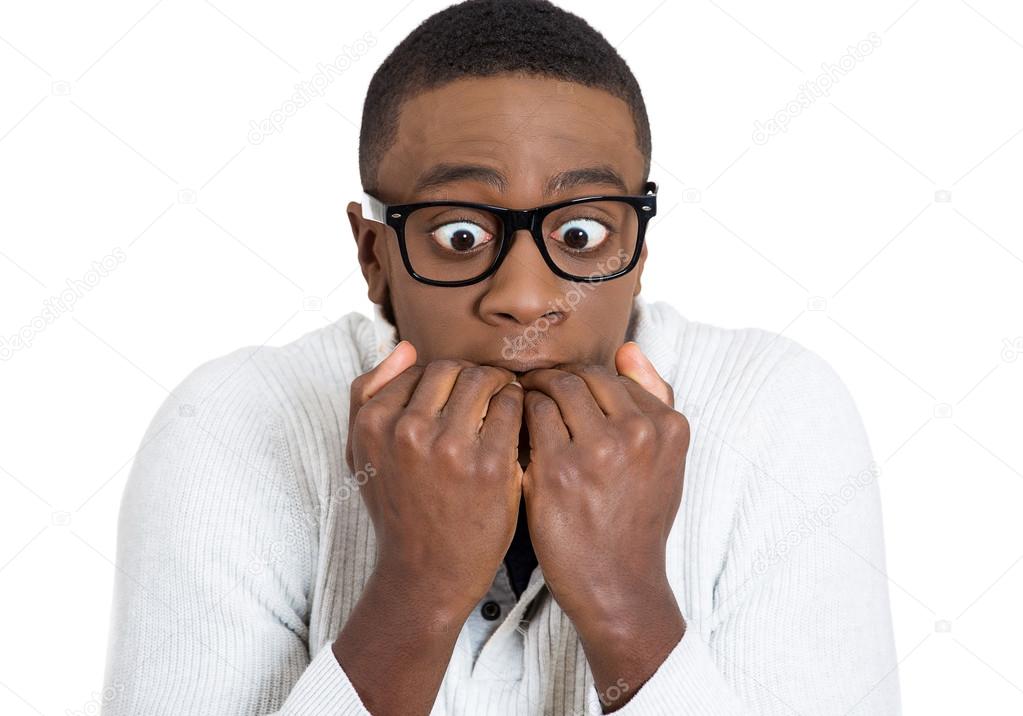 Shy unhappy guy with black glasses biting his nails looking scared 