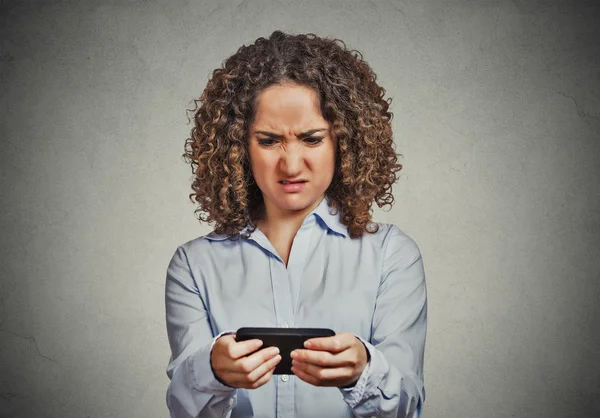 Unhappy woman texting on phone with disgusted face — Stock Photo, Image