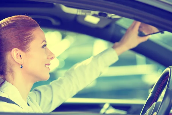 Donna conducente cercando regolazione posteriore vista auto specchio — Foto Stock