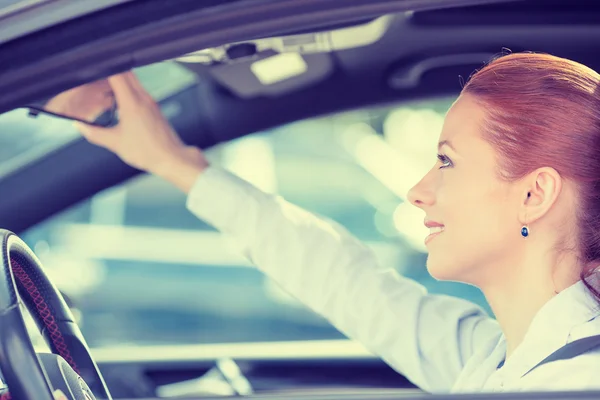 Donna conducente cercando regolazione posteriore vista auto specchio — Foto Stock