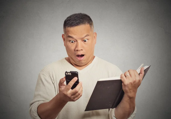 Geschockter Mann mittleren Alters schaut aufs Handy lizenzfreie Stockbilder