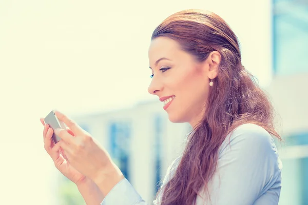 Mujer joven en camisa azul sosteniendo el uso de teléfono inteligente — Foto de Stock