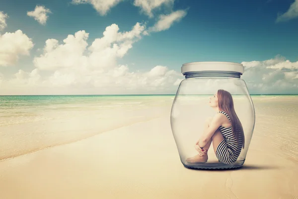 Woman sitting in a glass jar on a beach looking at the ocean view — Stock Photo, Image