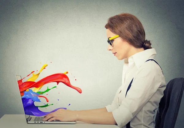 Mujer trabajando en la computadora salpicaduras de colores que salen de la pantalla —  Fotos de Stock