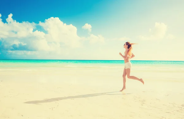 Junge Frau läuft am Sommerstrand an der Küste des Ozeans — Stockfoto