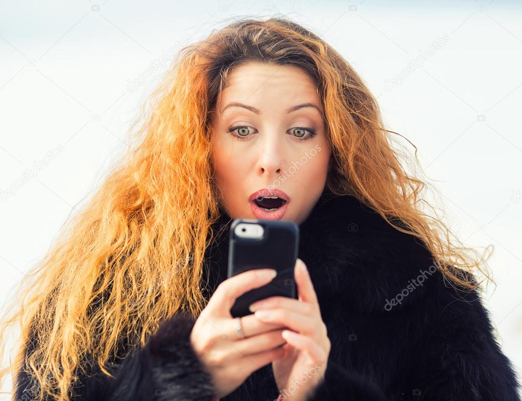 Shocked woman looking at mobile phone seeing bad news