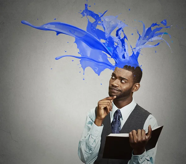 Thoughtful businessman reading book colorful splashes coming out of head — Stock Photo, Image