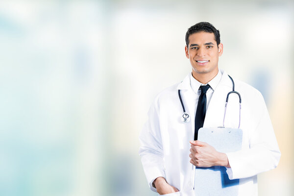 happy confident young medical doctor standing in hospital hallway