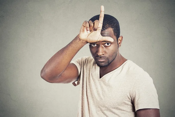 Hombre mostrando signo de perdedor en la frente mirándote — Foto de Stock