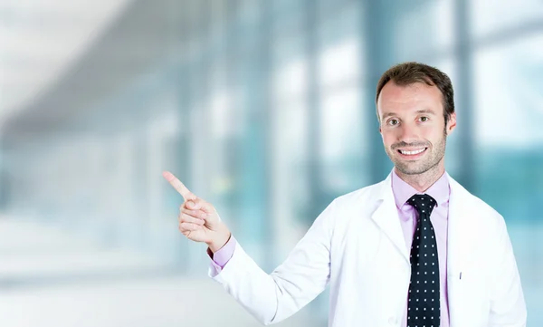 Zufriedener männlicher Arzt lächelt und zeigt mit erhobenem Finger nach oben — Stockfoto