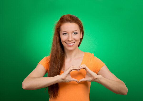 счастливая молодая женщина делает сердечный знак руками

