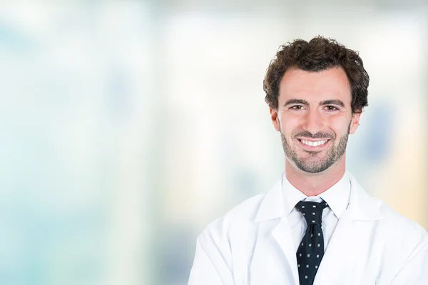 Young male doctor smiling standing in hospital hallway — Stock Photo, Image