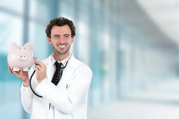 Miling doctor holding listening a piggy bank with stethoscope — Foto de Stock