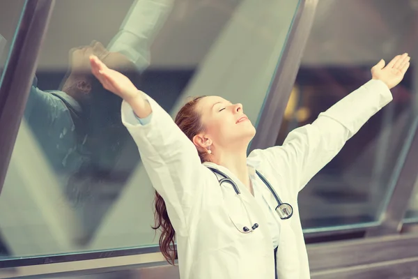 Joyful female doctor standing in hospital hallway with arms raised — Stock Photo, Image