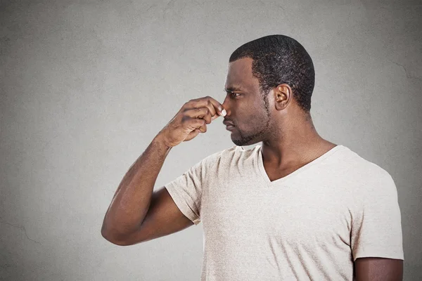 Portrait man with disgust on face pinches nose something stinks — Stock Photo, Image