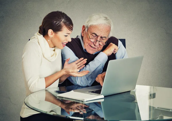 Woman teaching confused elderly man how to use laptop — Stock Photo, Image