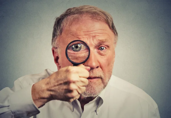 Nahaufnahme überrascht Mann, der durch ein Vergrößerungsglas schaut — Stockfoto