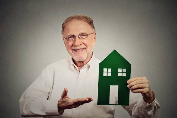 Старший счастливый человек представляет зеленый дом — стоковое фото