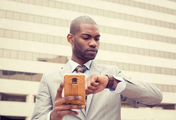 Hombre de negocios mensajes de texto en el teléfono móvil y mirando su reloj —  Fotos de Stock