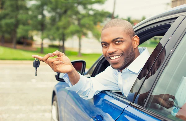 Felice, sorridente, giovane seduto nella sua nuova auto che mostra le chiavi — Foto Stock